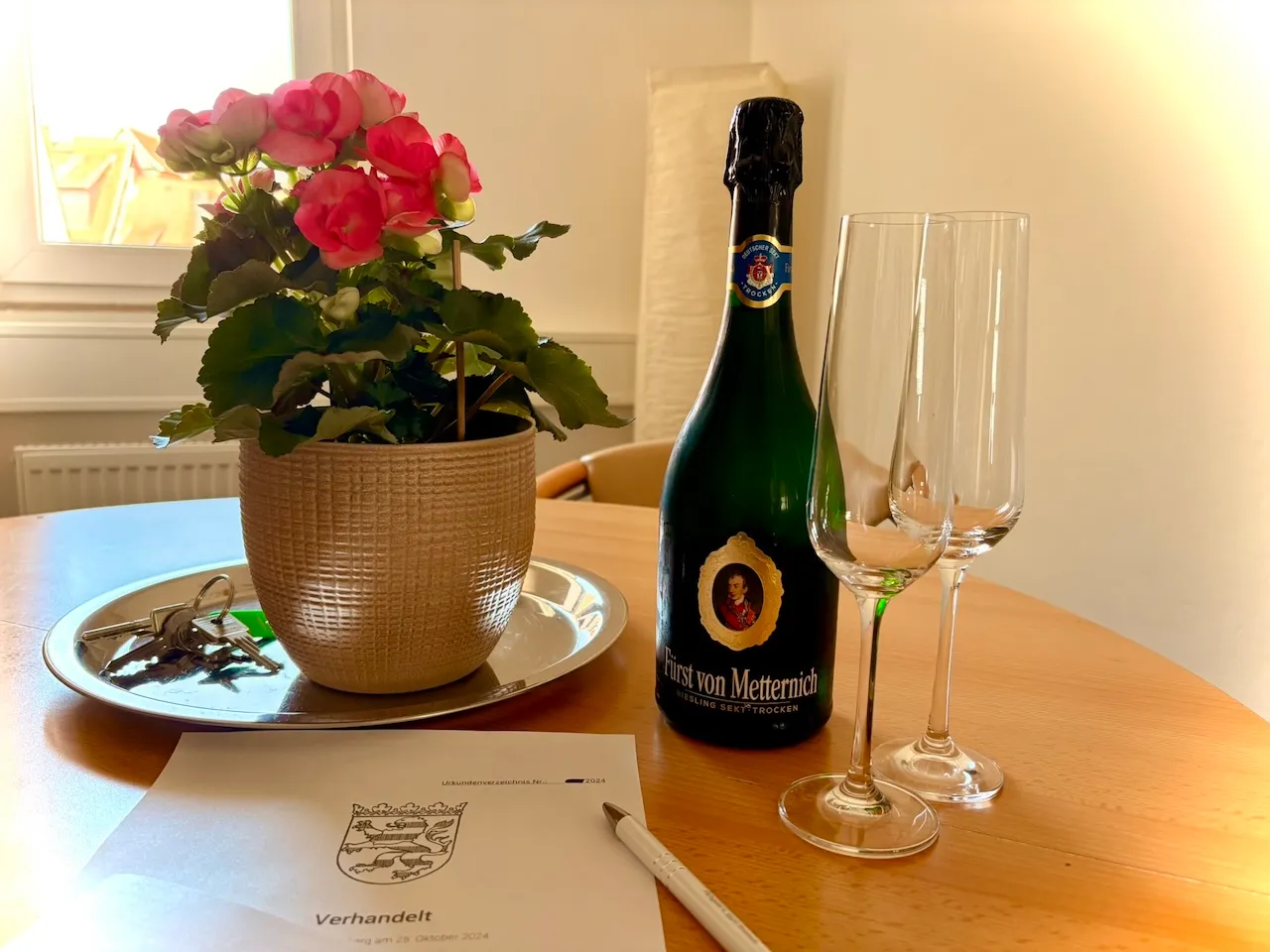 Patzina Immobilienverwaltung GmbH- Vertragsunterlagen mit Stift auf dem Tisch neben Blumenvase, Schlüsseln und Wein
