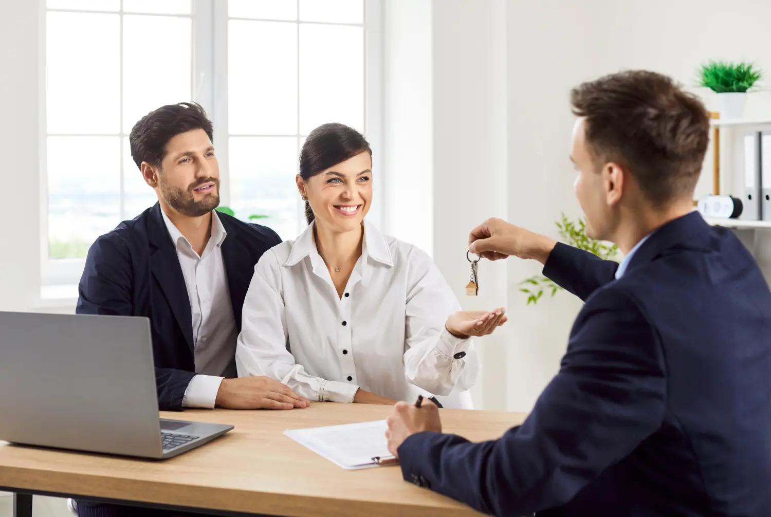 Glückliche Familie, Paar erhält Schlüssel vom Immobilienmakler, Agent zum Kauf einer neuen Immobilie im Büro einer Immobilienagentur